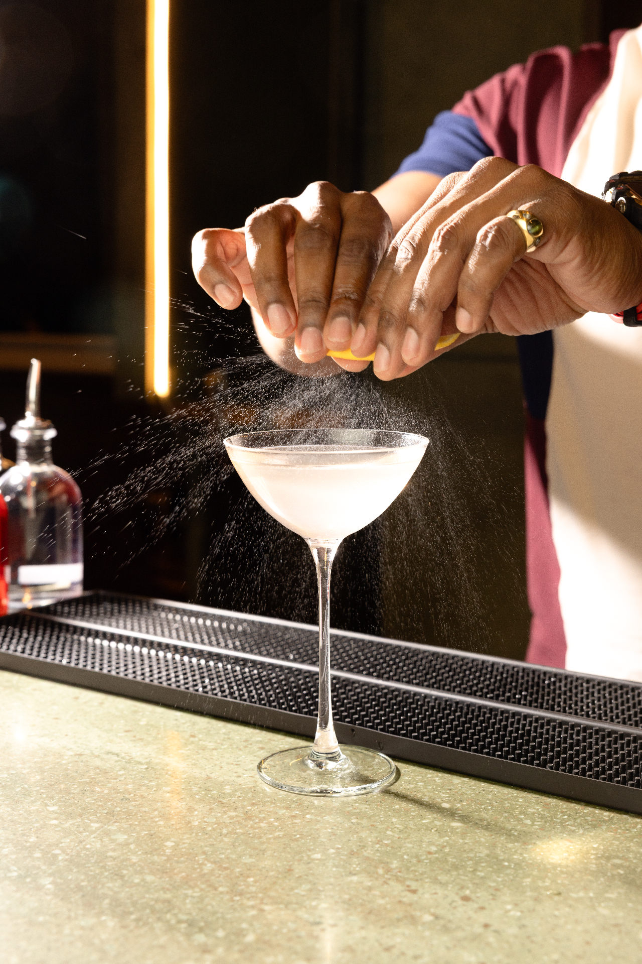 Bartender expressing a citrus twist over a coupe cocktail